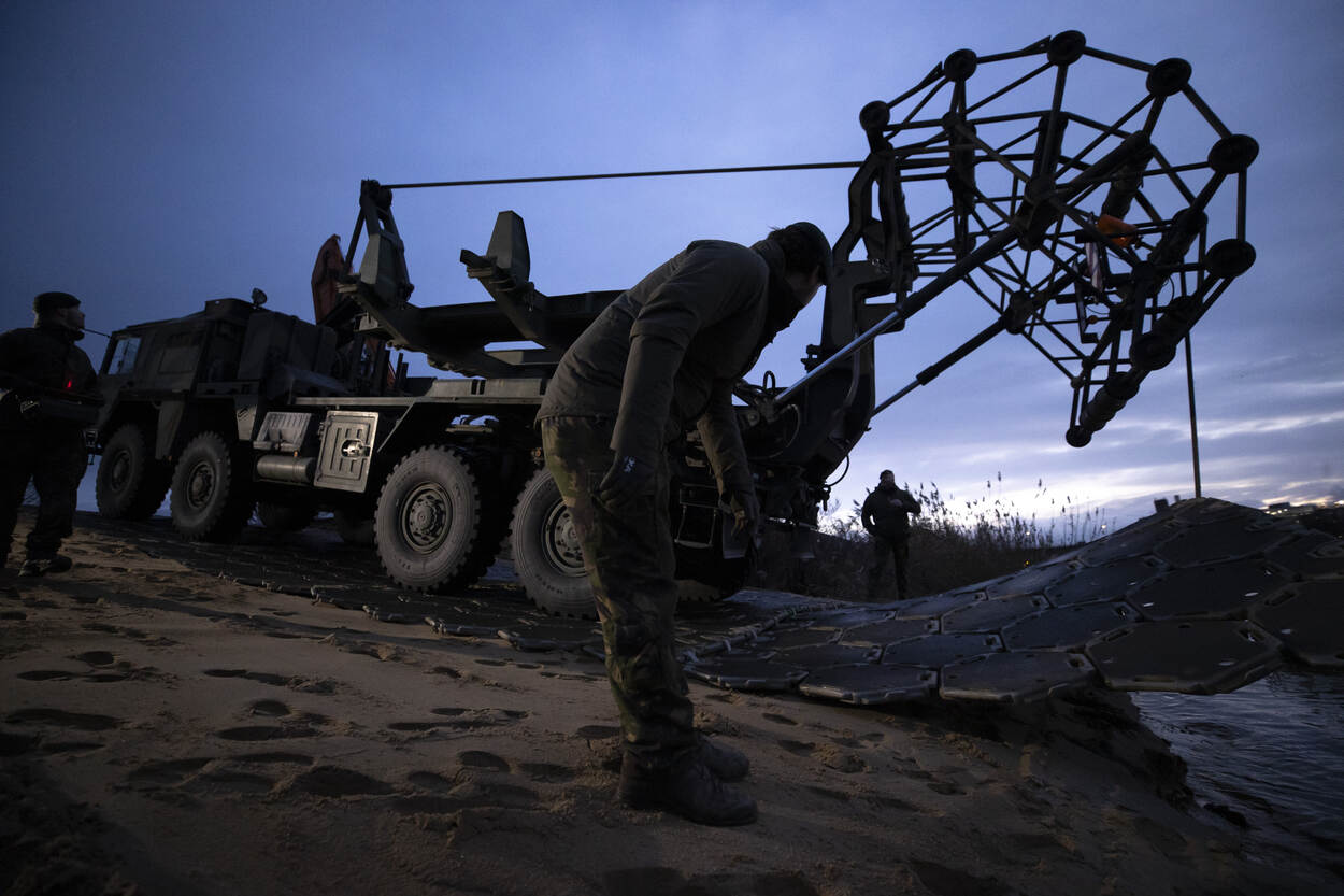 De mattenlegger van 105 Genietroepen waterbouw legt een mat aan de oever van de Maas.