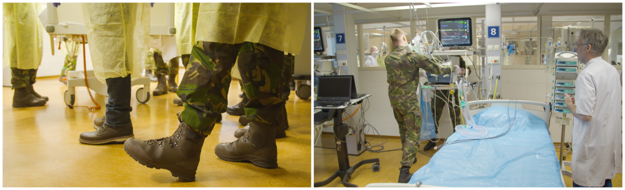De onderbenen van militairen met beschermende hygiënejas aan en een behandelruimte in het Calamiteitenhospitaal.