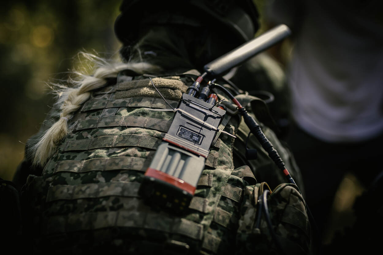 Een radio, op de rug van een militair, die vaag erachter te zien is.