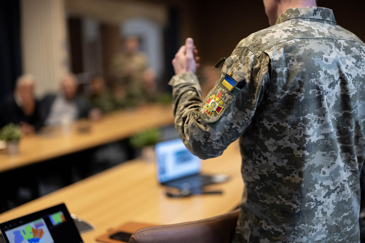 Torso van een Oekraïense militair, van de achterkant bezien. Op de arm prijkt de geelblauwe Oekraïense vlag.