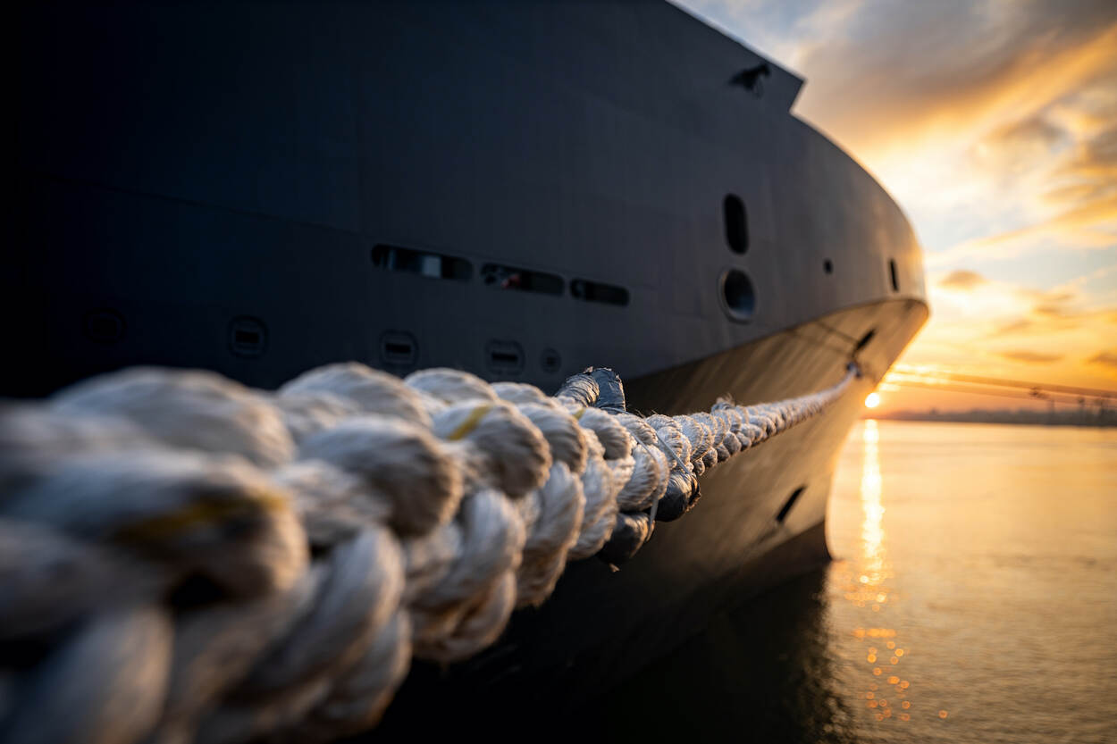 close-up van de trossen waarmee het CSS vastligt aan de kade, terwijl de zon zakt.