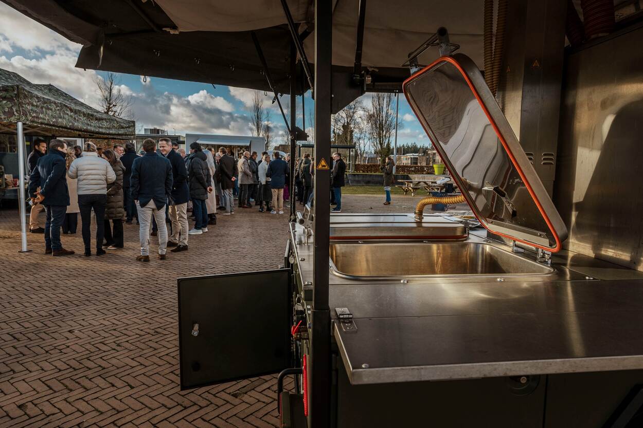 een close up van een veldkeuken met op de achtergrond pratend publiek.