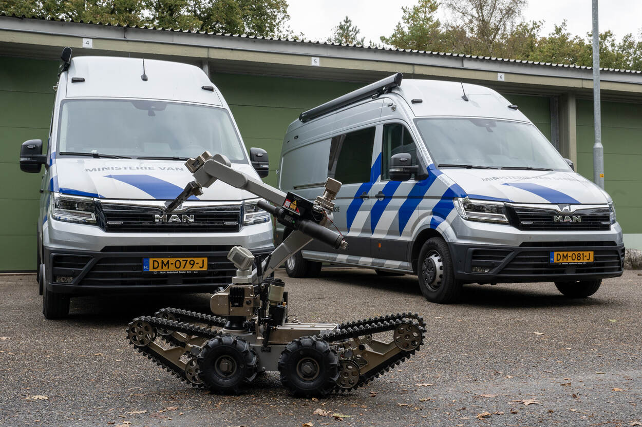 Twee werkbussen van de EOD met een onderzoeksrobot op de voorgrond.