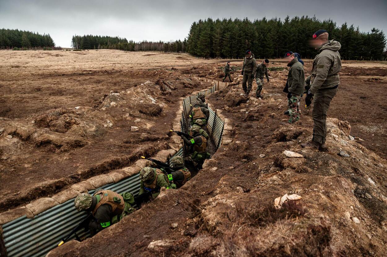 Oekraïense militairen oefenen in een loopgraaf. Nederlandse militaire instructeurs kijken toe.