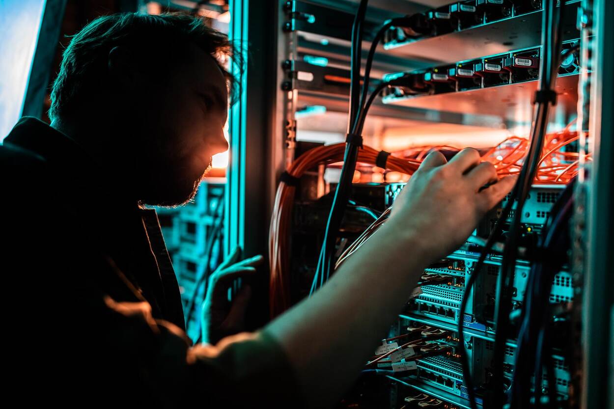 Een militair is bezig met de achterkant van een kast vol computerservers.