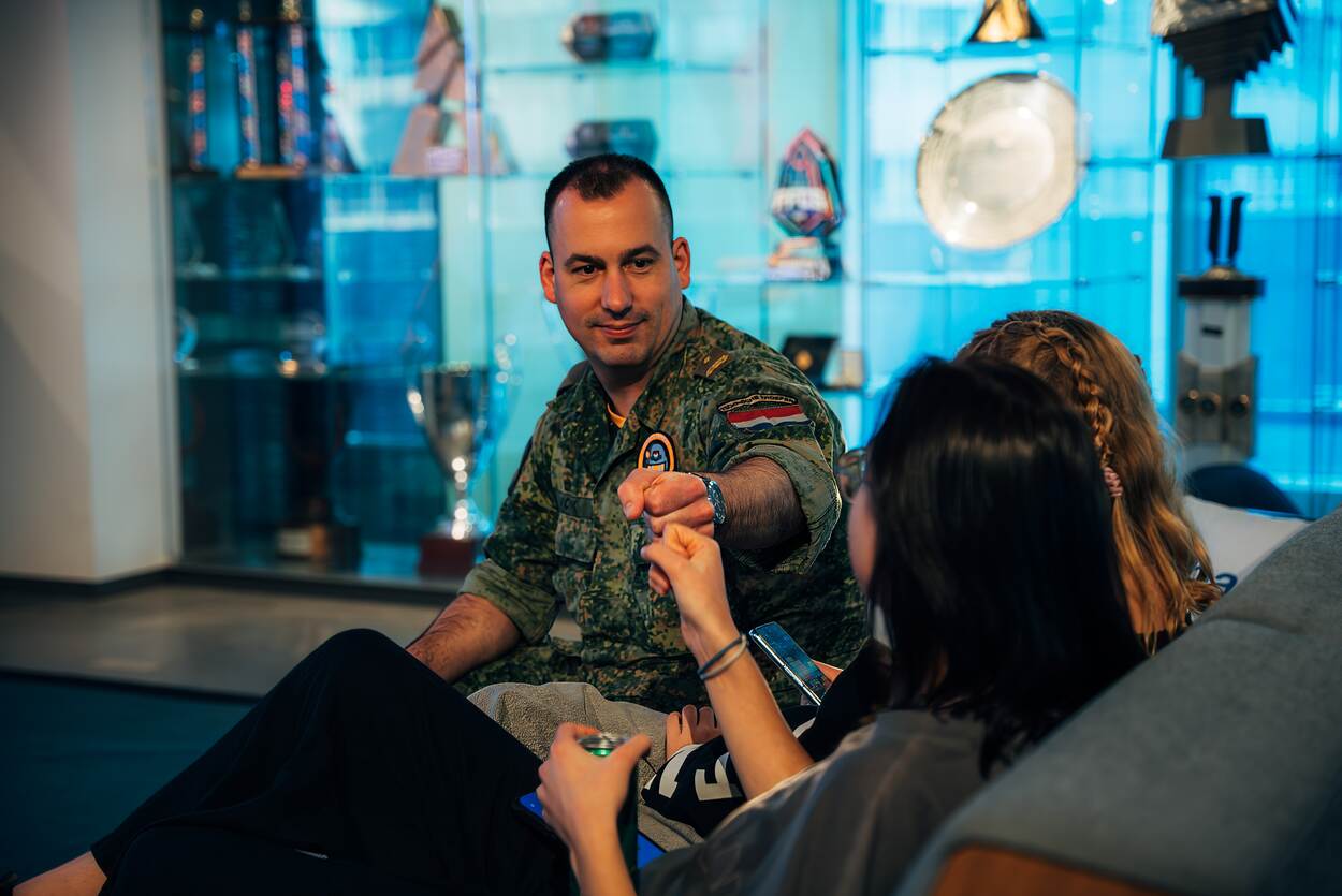 Militair geeft boks aan jongere op een bank.