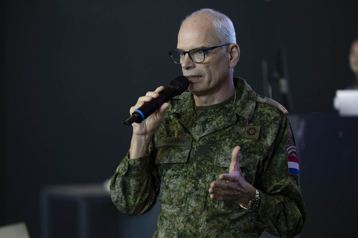 Brigadegeneraal van der Touw in gevechtspak, met microfoon in hand.