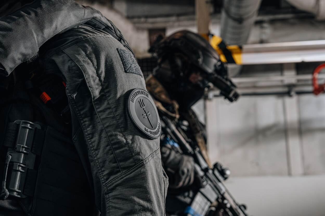 een close up van een mouwembleem met daarop de tekst ‘Interventie M-Squadron’.