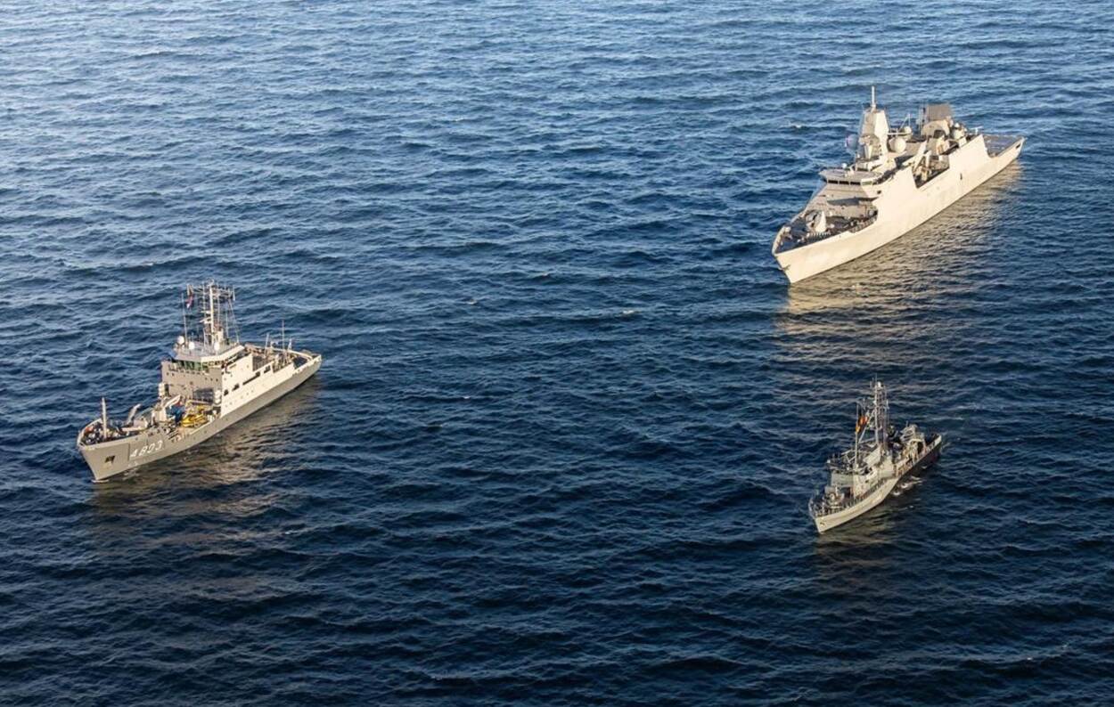 3 marineschepen varen op zee.