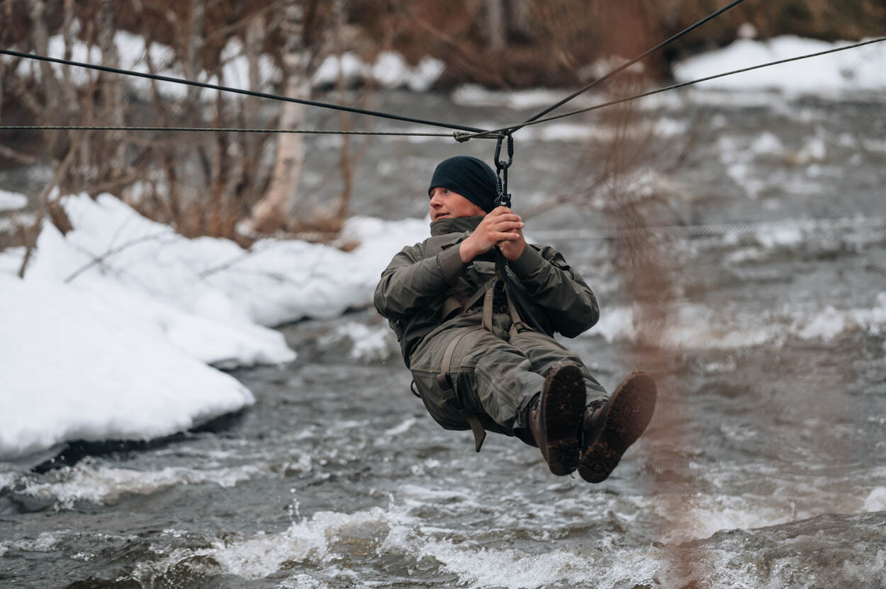 Een marinier gaat aan een lijn de rivier over