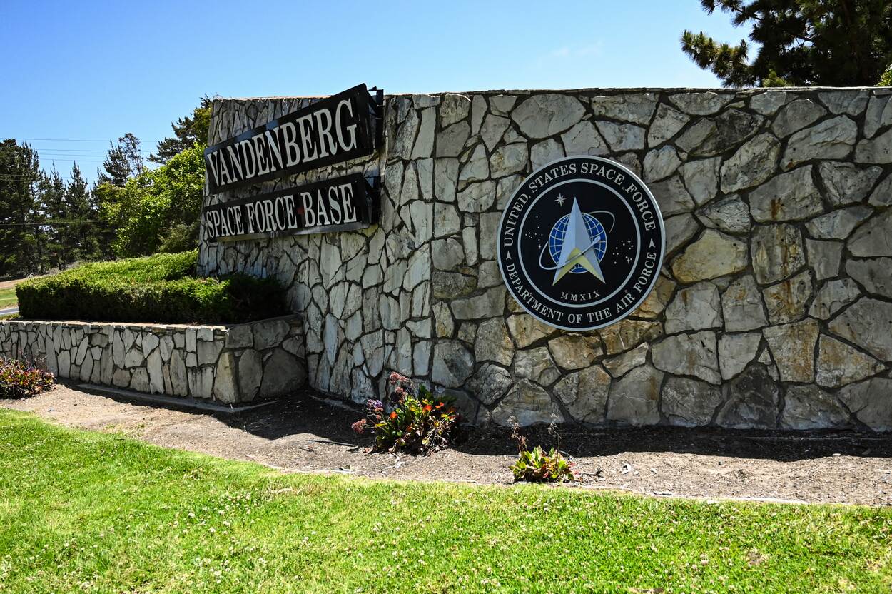 Een stenen muurtje met daarop de tekst Vandenberg Space Force Base, daarnaast het logo ervan.