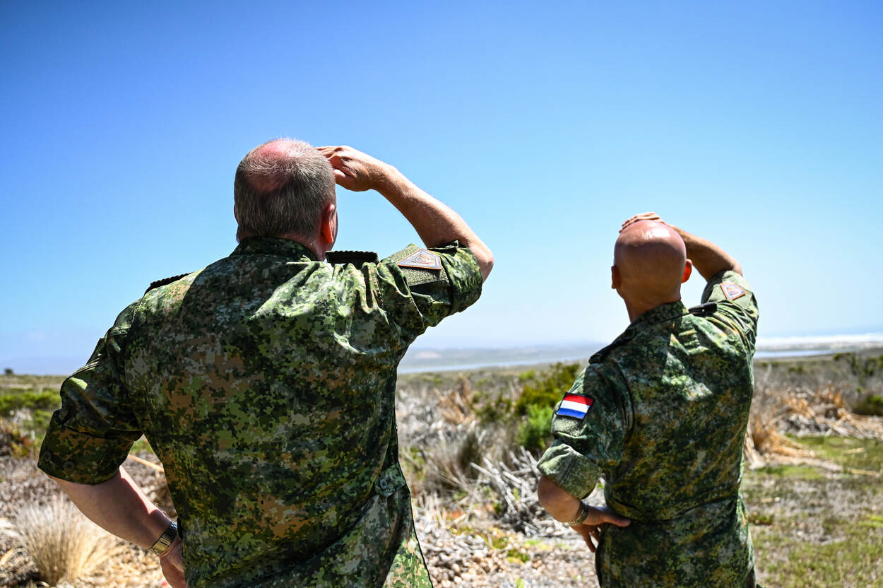 Twee militairen kijken omhoog na de lancering van een satelliet.