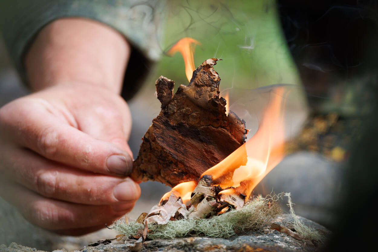 Handen bij een beginnend vuurtje.