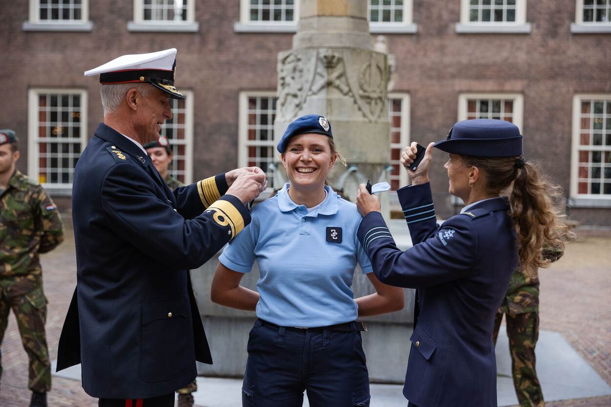 Een marechaussee krijgt op beide schouders nieuwe rangonderscheidingstekens geïnstalleerd.