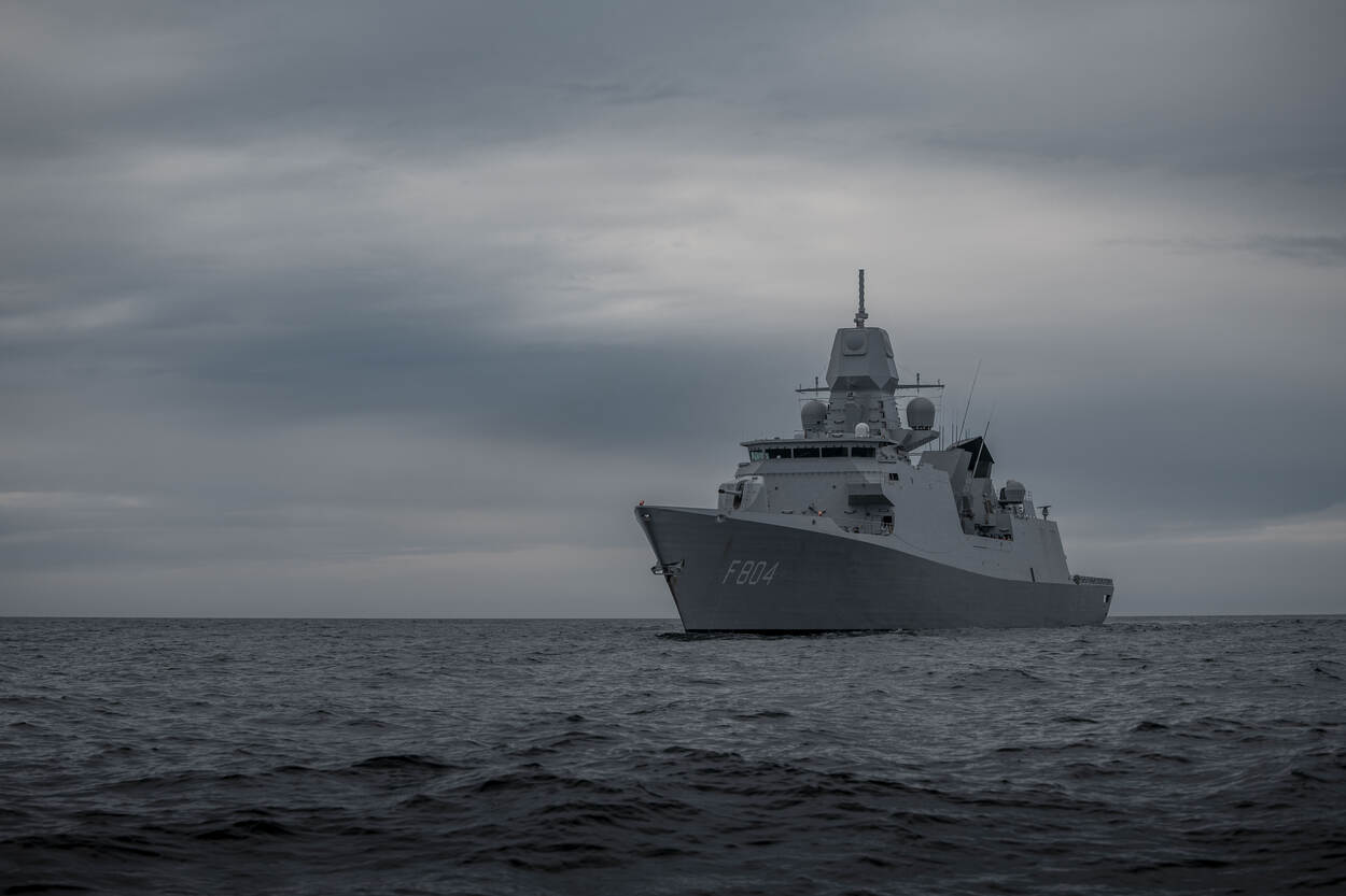 Een marineschip ligt stil op een rustige zee.