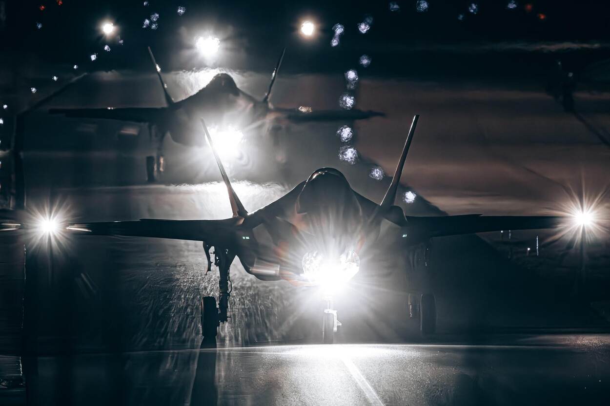 Twee F-35’s taxiën in het donker over een start- en landingsbaan.