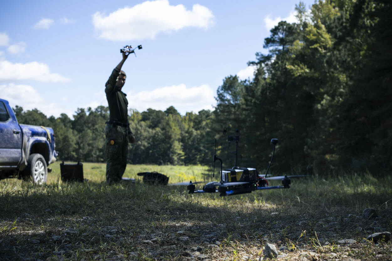 Een militair houdt een drone in de lucht.