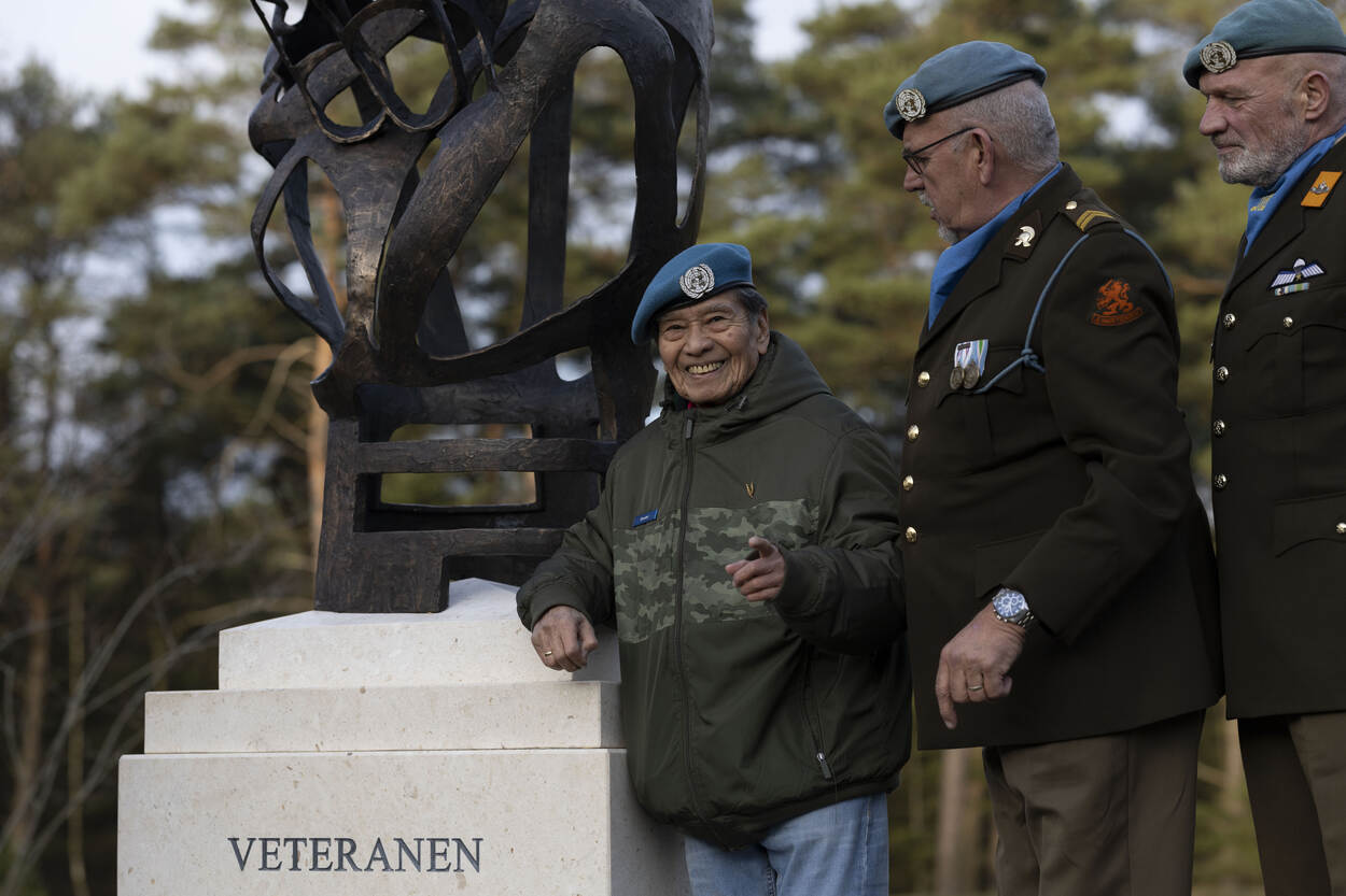 Veteranen staan bij een nieuw monument op de veteranenbegraafplaats in Loenen; op de sokkel staat het woord ‘Veteranen’ en één veteraan glimlacht naar de camera.
