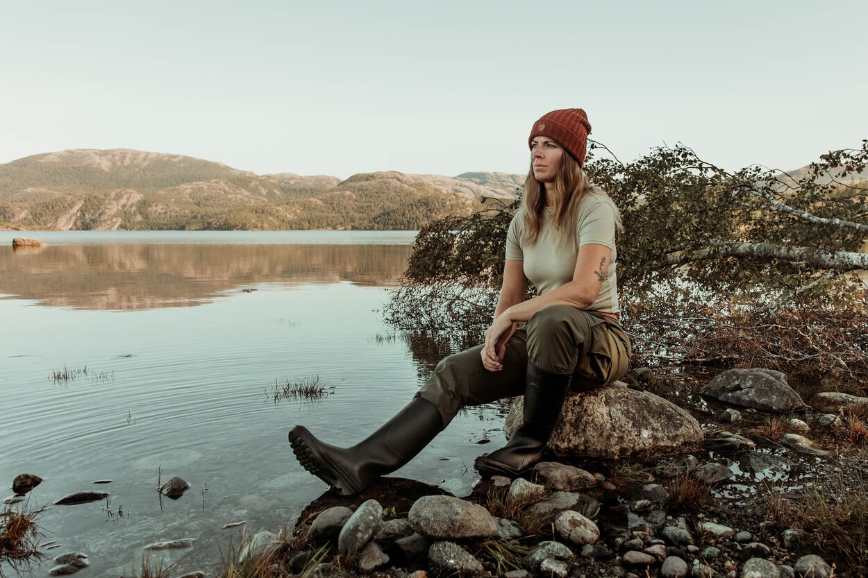 Majoor Marie-José Spek zit in outdoorkleding aan de rand van een meer in Noorwegen.