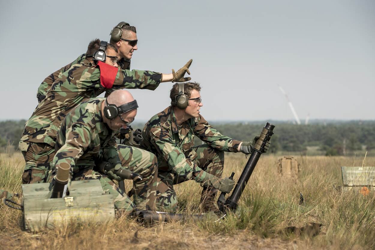 Archieffoto van vier mariniers, staand achter een mortierafvuursysteem.