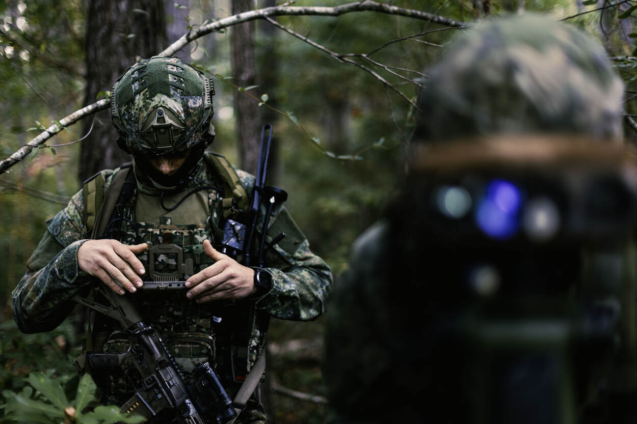 Een marinier kijkt naar het scherm dat aan zijn borst hangt. Zijn collega voor hem kijkt door een gyroscoop.