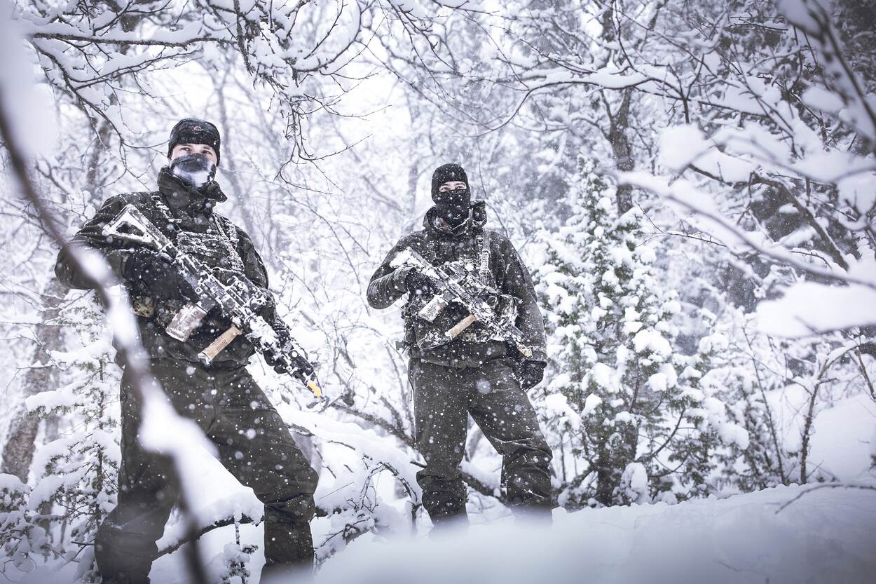 Twee mariniers met wapen voor het lichaam in een besneeuwd bosje.