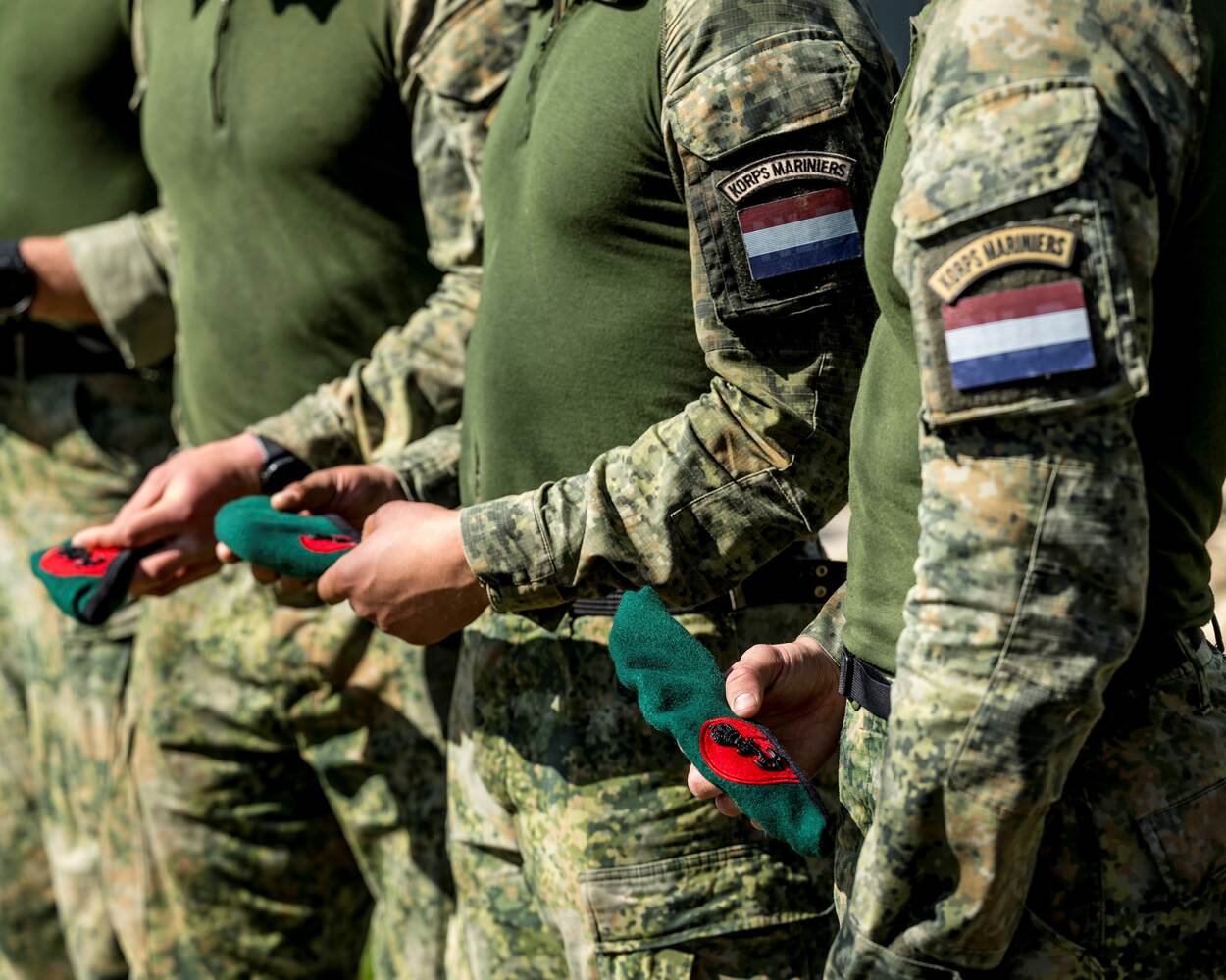 Mariniers op een rij met de groene baret in de hand.
