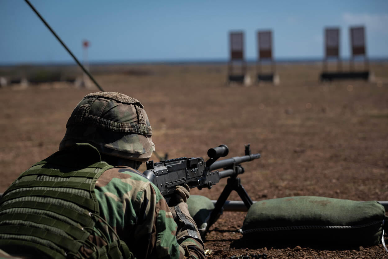 Een Caribische militair neemt met een MAG-mitrailleur een doel op de schietbaan onder vuur.