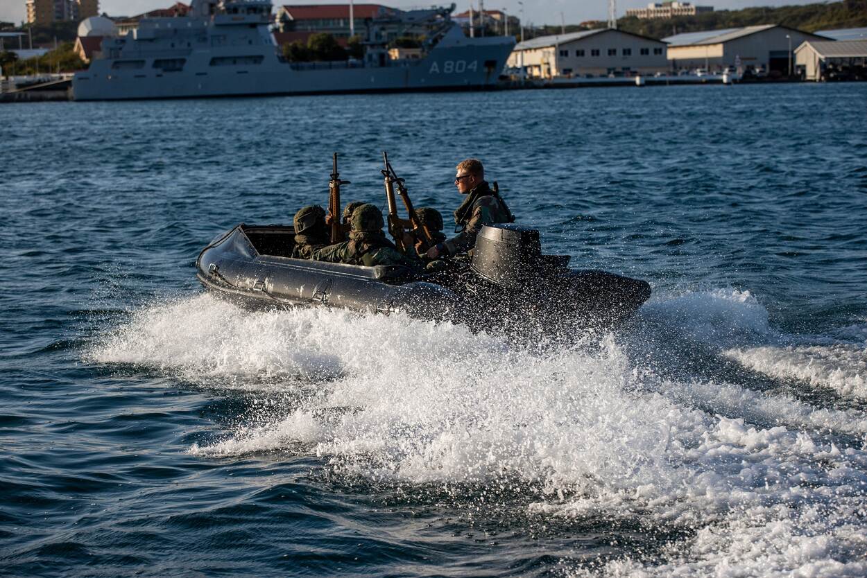Een Nederlandse militair zittend in een rubberboot met Caribische Militairen.
