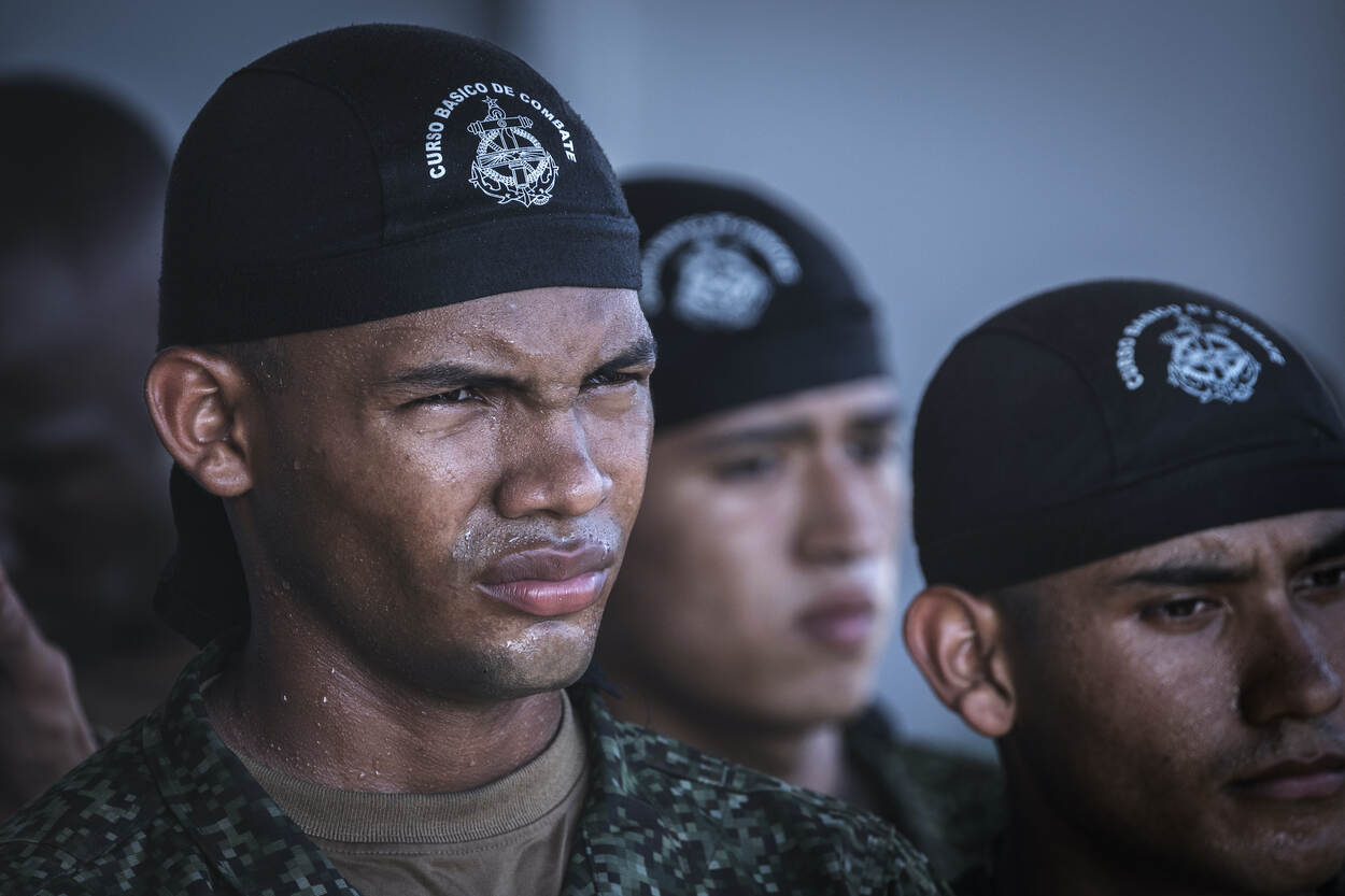 Colombiaanse mariniers met een zwarte bandana om hun hoofd luisteren naar een briefing.