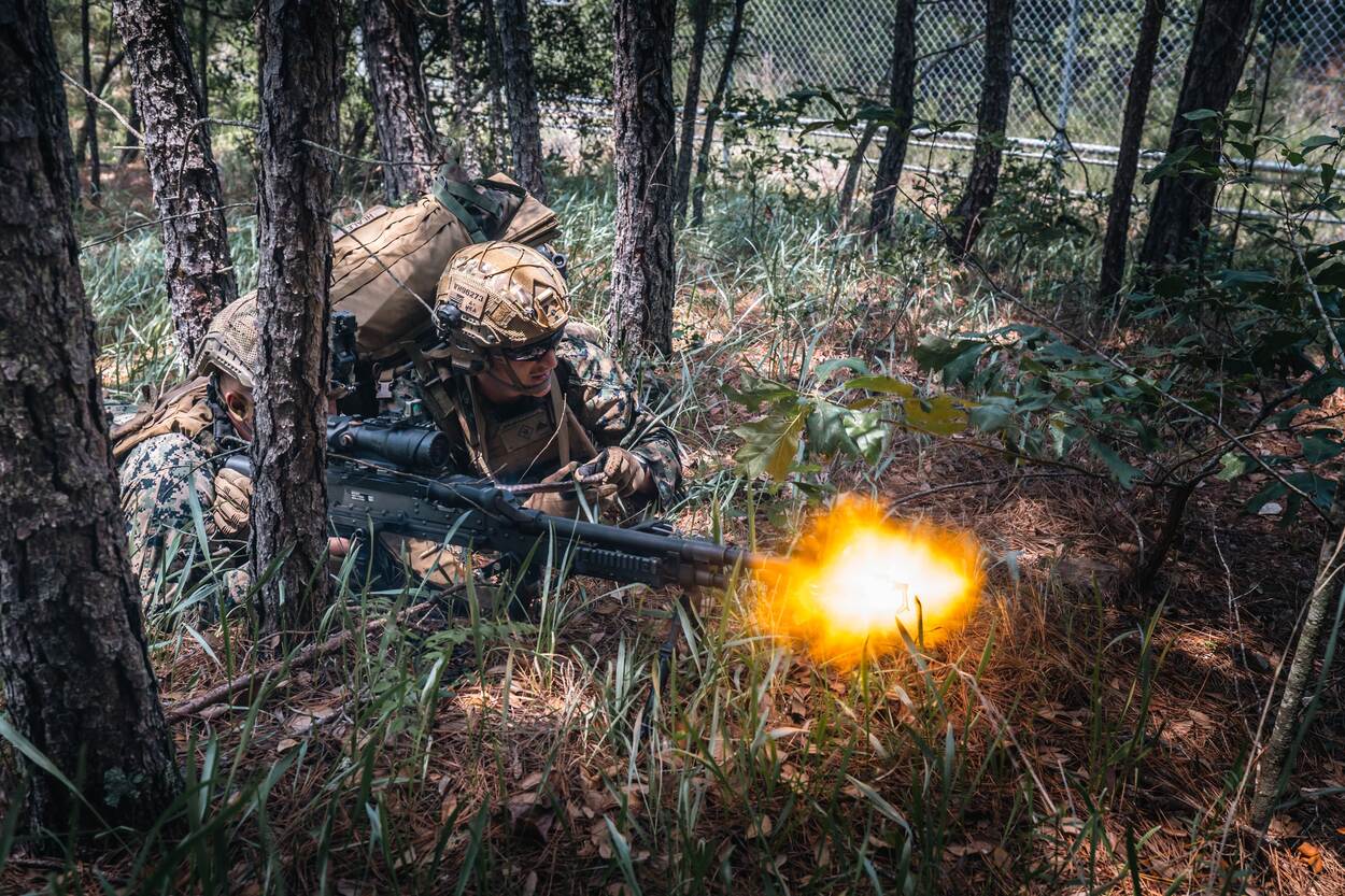Twee mariniers in het bos, een van hen vuur met zijn MAG.