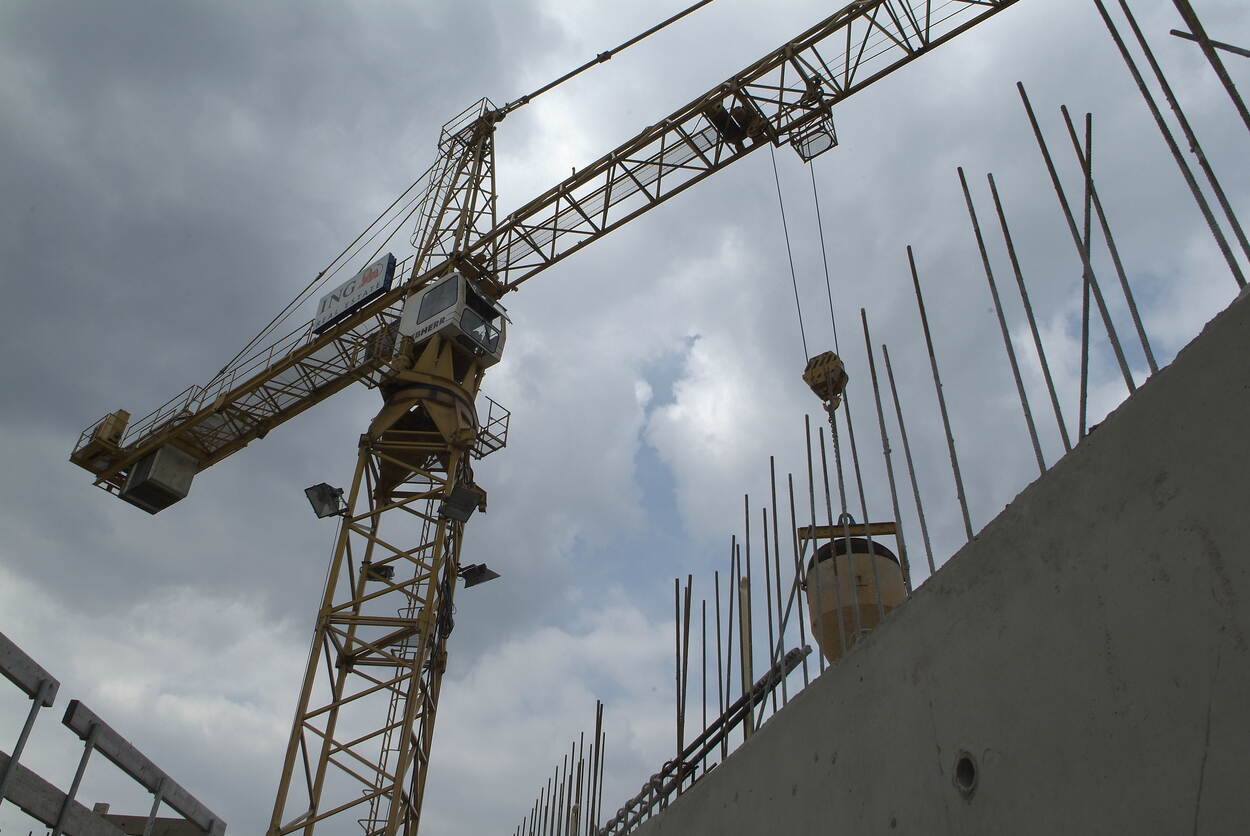 Een bouwkraan steekt hoog uit boven een bouwplaats.