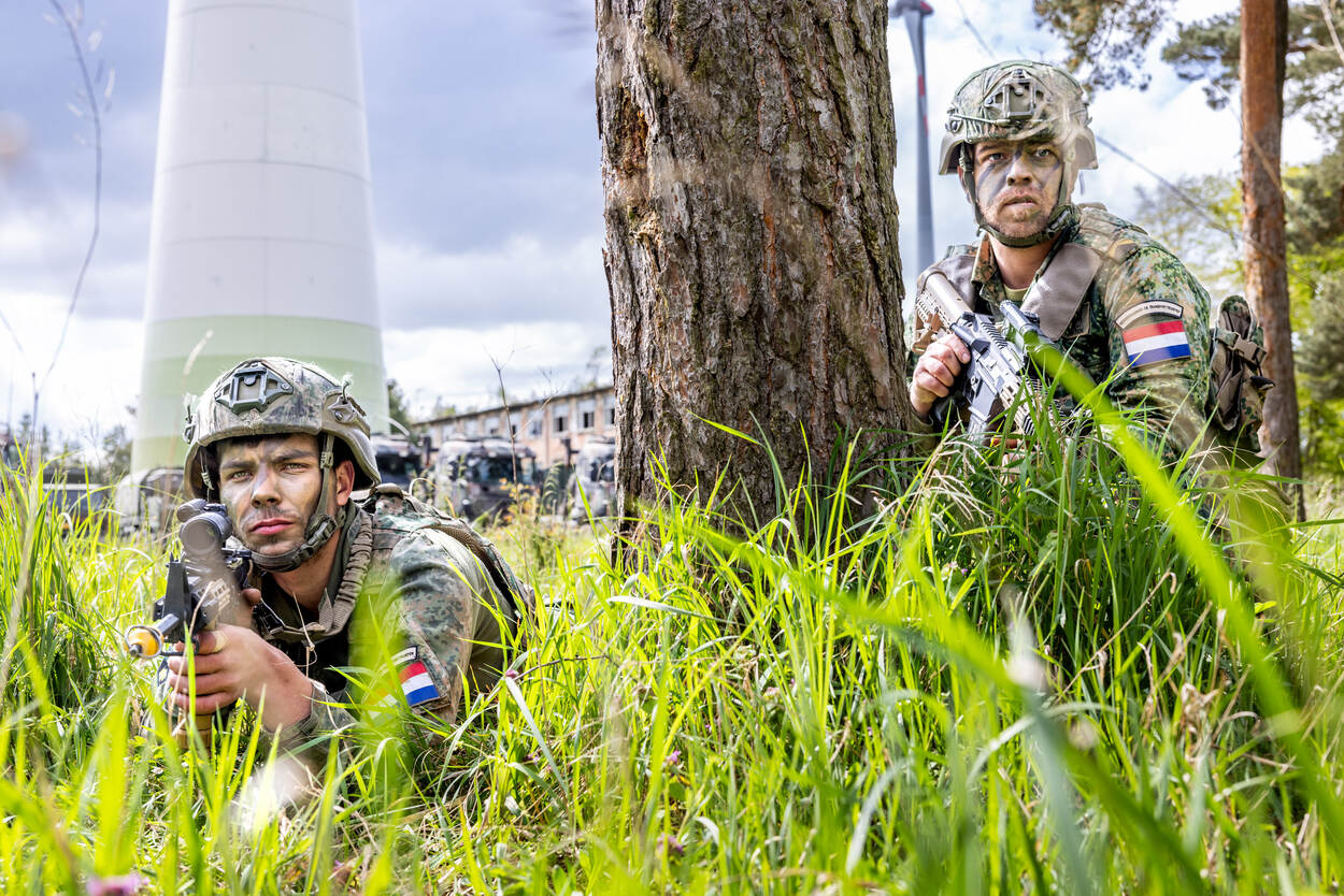 Militairen van de Bevoorrading en Transport liggen gewapend voor de vrachtwagens van hun compagnie.