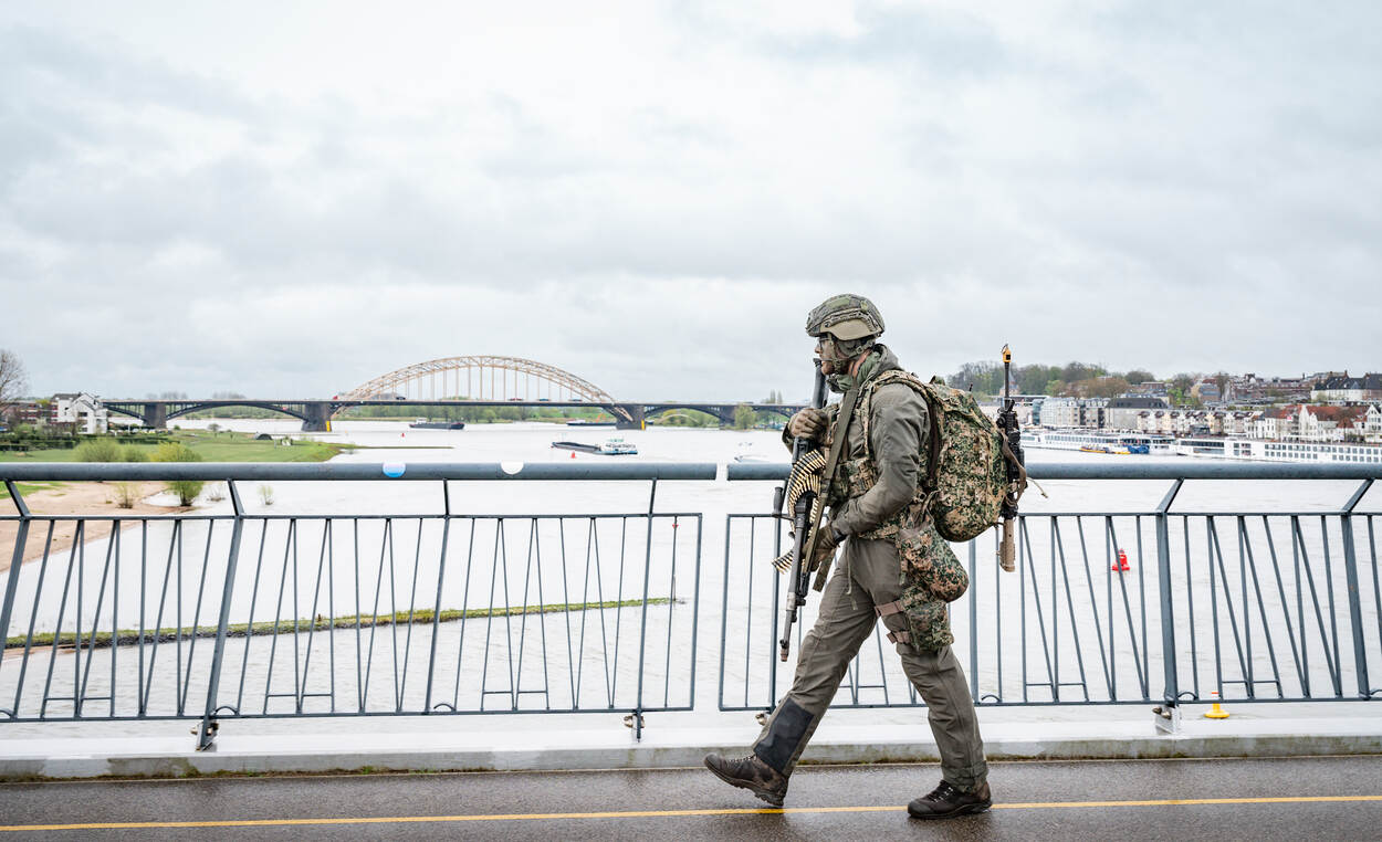 een militair steekt een brug over de Waal over.