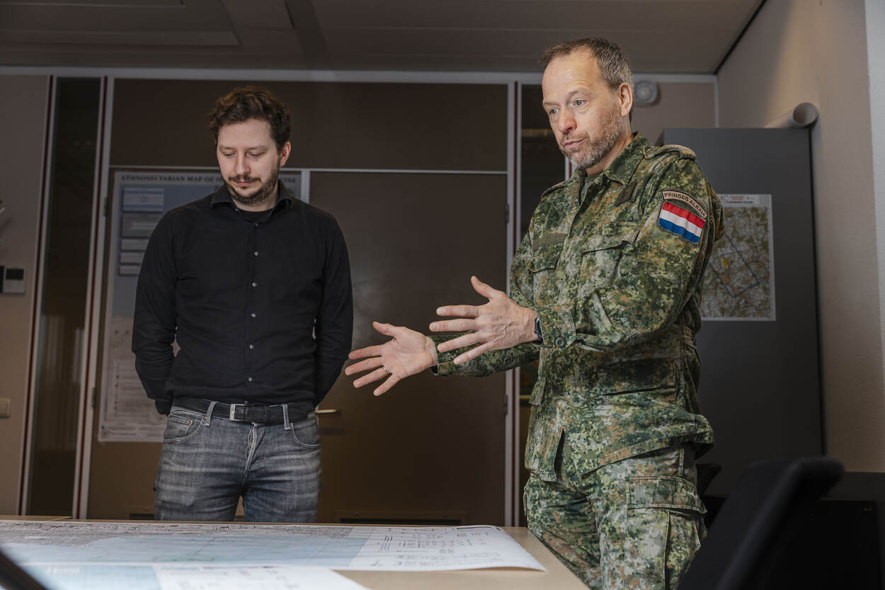 Overste Clemens Roos en geo-informatie adviseur Paolo Kors staan bij een tafel vol kaarten.