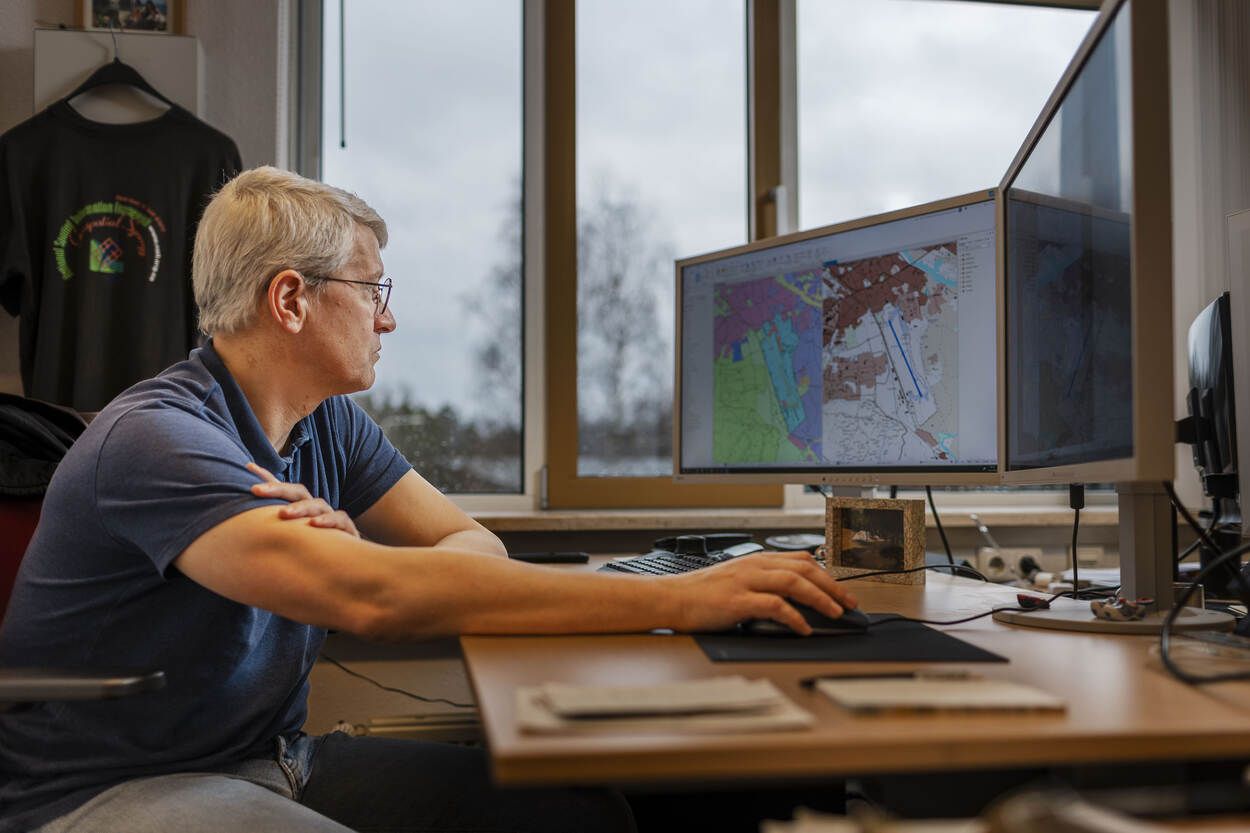 Een medewerker kijkt op een beeldscherm naar een van de door DGeo gemaakte kaarten.