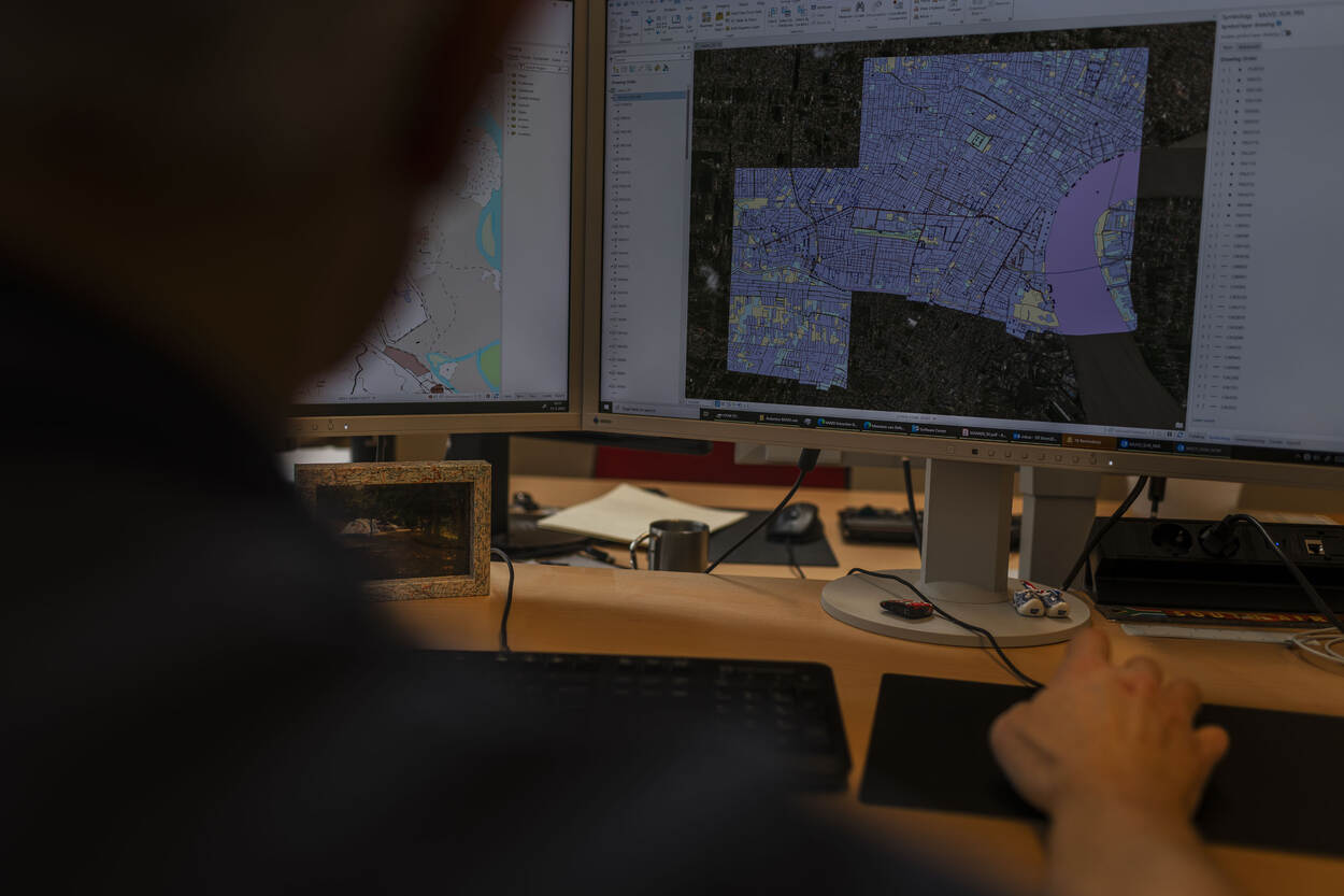 Een medewerker van DGeo met op de achtergrond een digitale kaart op de computer.