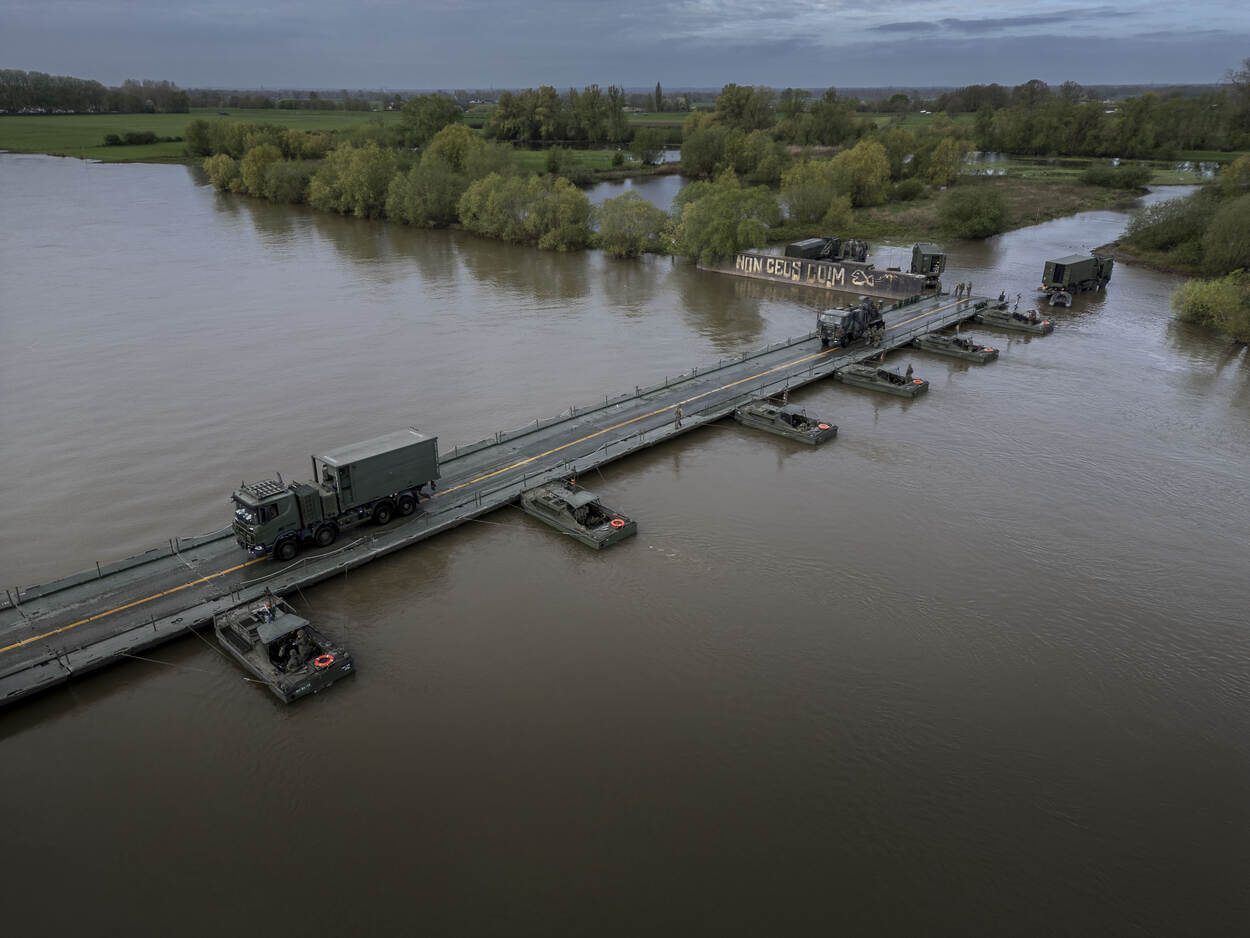 Voertuigen rijden over een brug die op het water is gelegd.