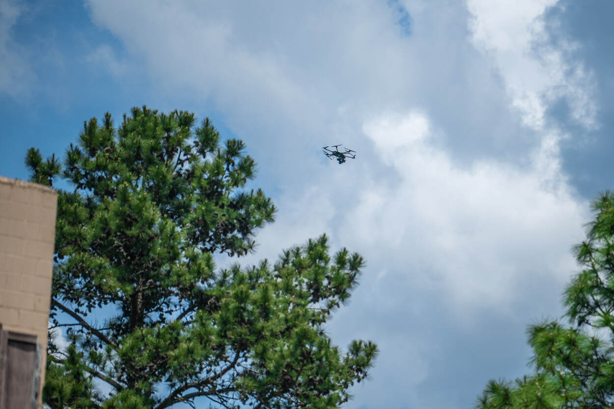 Foto links: een militair kijkt door een raam van een gebouw naar buiten, met zijn lange wapen voor het gezicht. Rechts: een drone vliegend in de lucht.