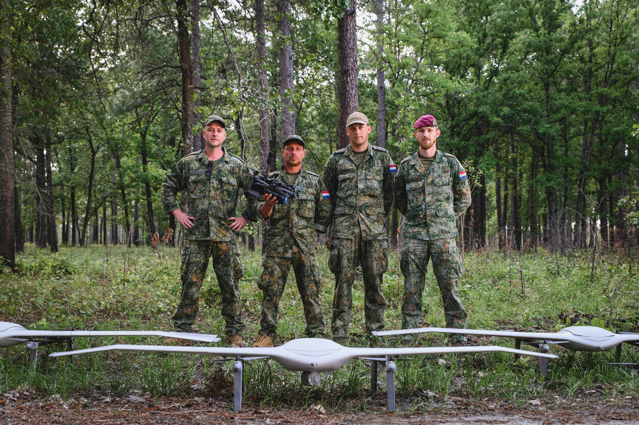 Foto links: een viertal militairen kijkt in de camera. Voor hen staan witte, grote drones. Foto rechts: een drone vliegt door de lucht, op het dak van een gebouw kijken mensen naar het vliegende vaartuig.