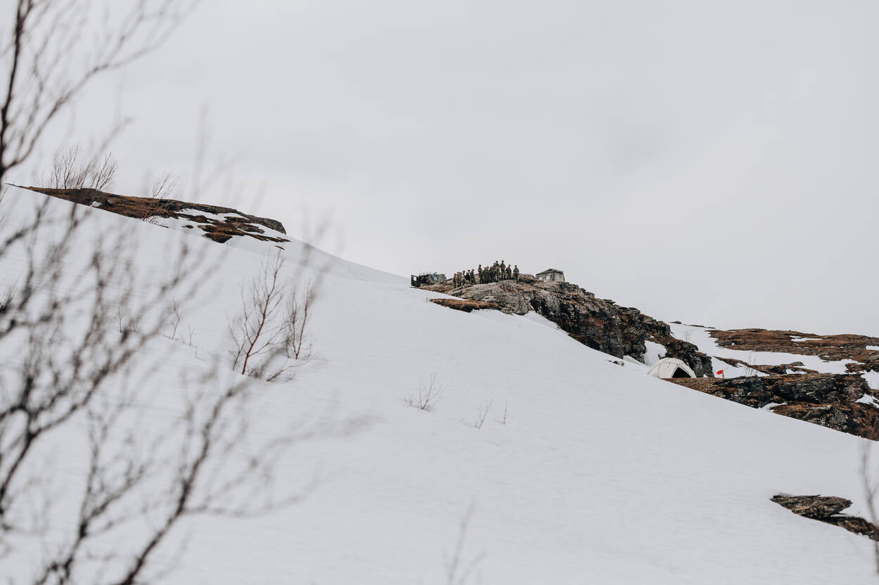 Witte besneeuwde helling met in de verte een groepje militairen