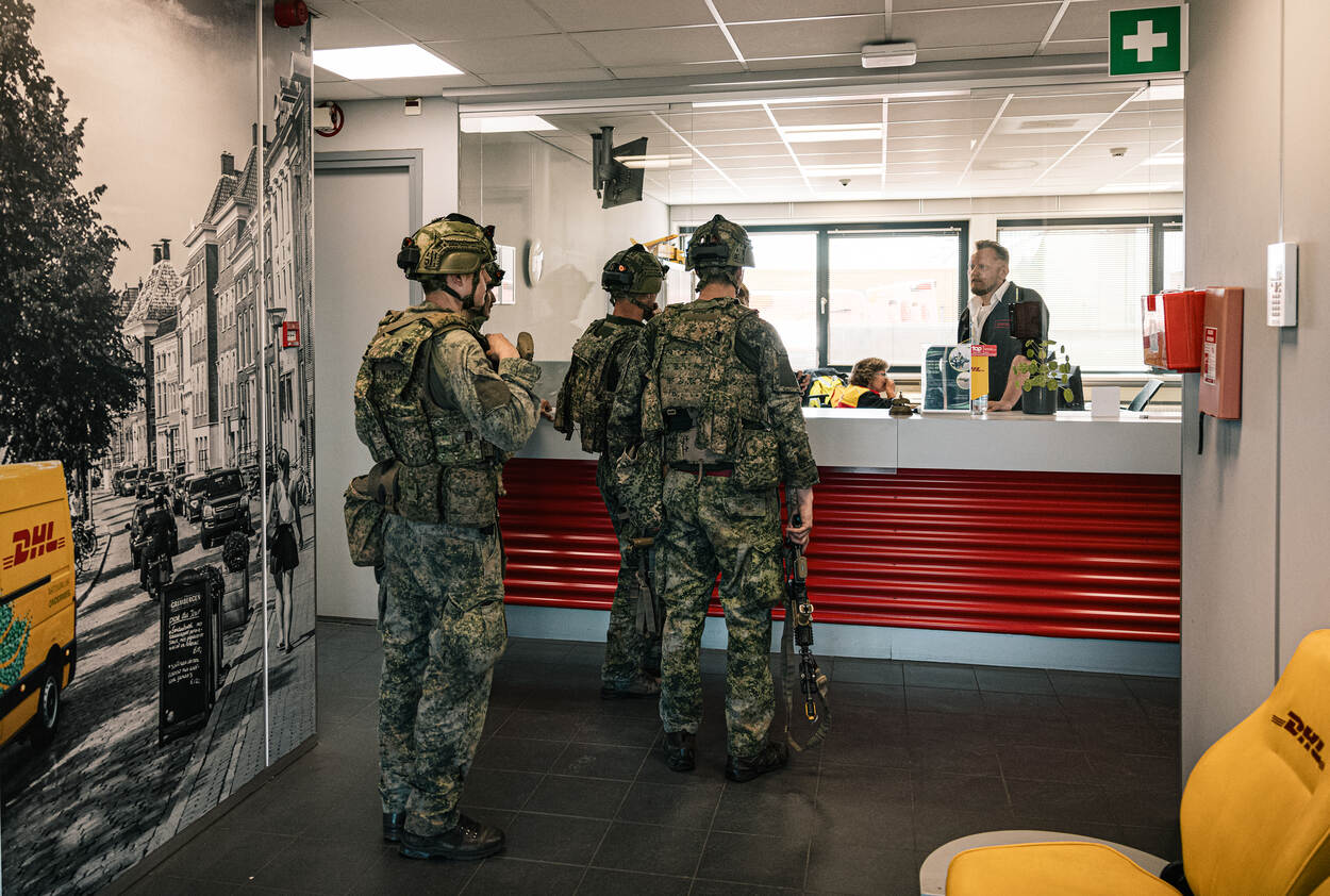 Militairen in gesprek bij een DHL-loket.