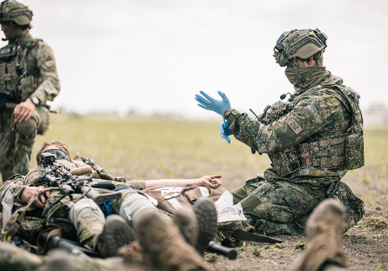 Een medic verzorgt een militair.