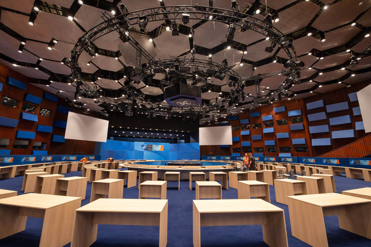Congreszaal NAVO-top vol met tafels en verlichting.