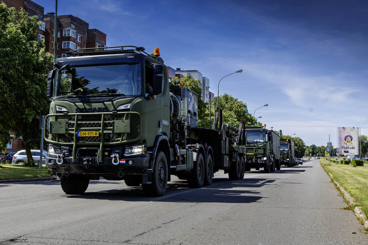 Een vooraanzicht van enkele vrachtwagens die achter elkaar in een Litouwse stad rijden.