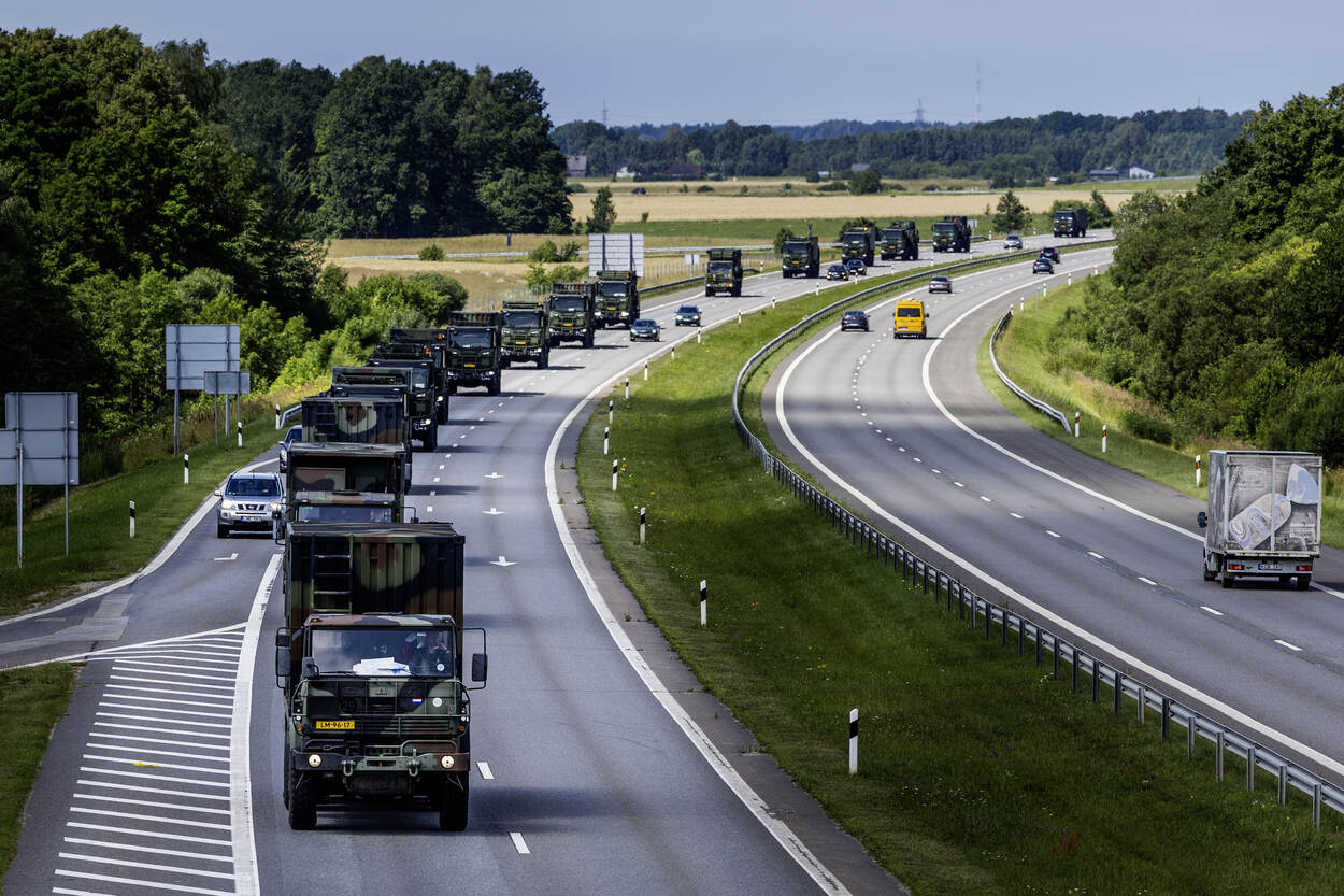 Een colonne militaire voertuigen op een snelweg.