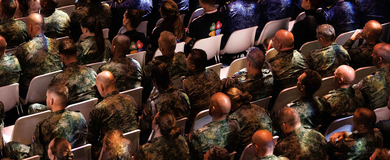 Een rij deelnemers in de zaal van bovenaf gezien.