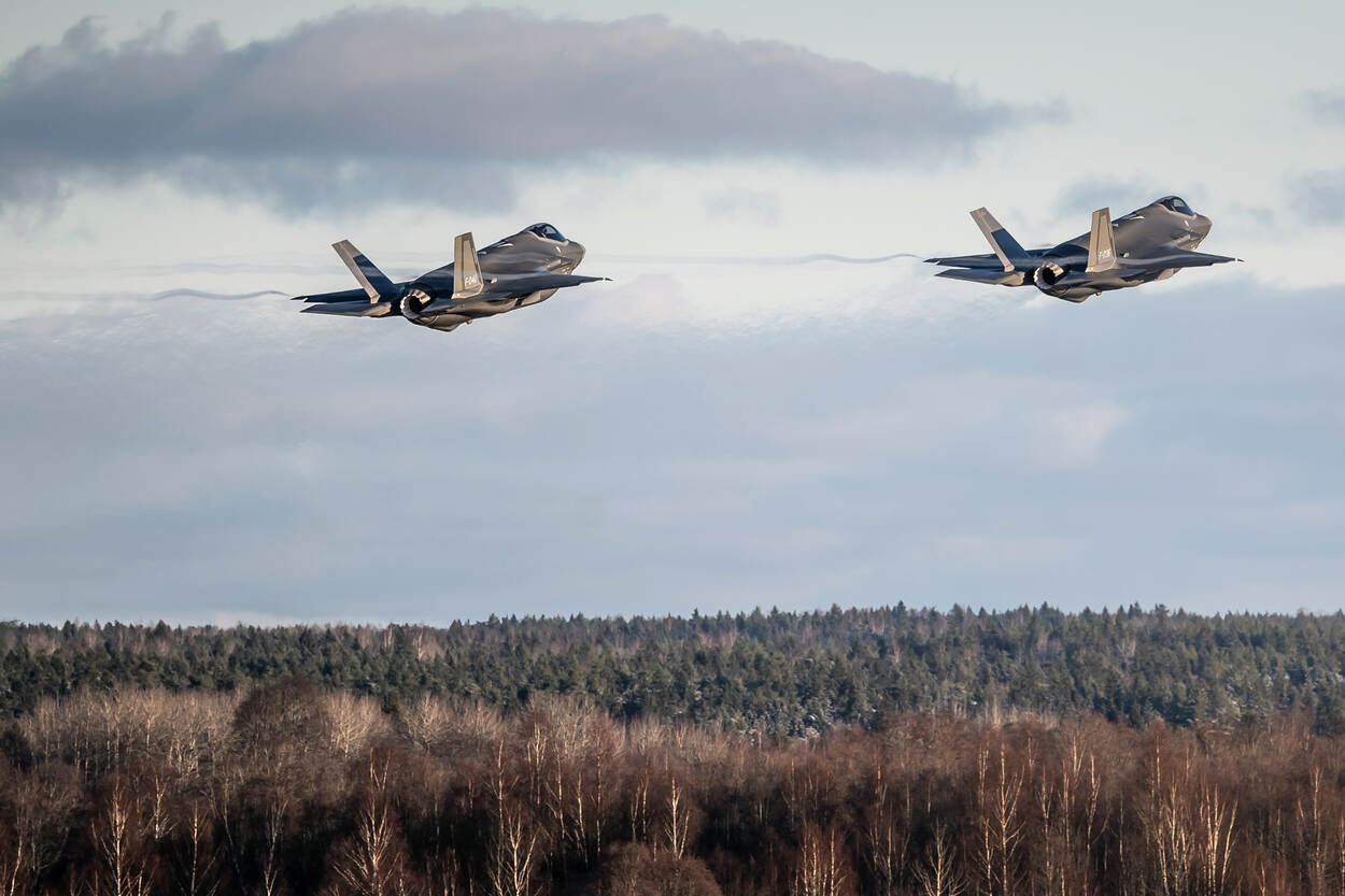 Twee F-35’s vliegend boven bomen.