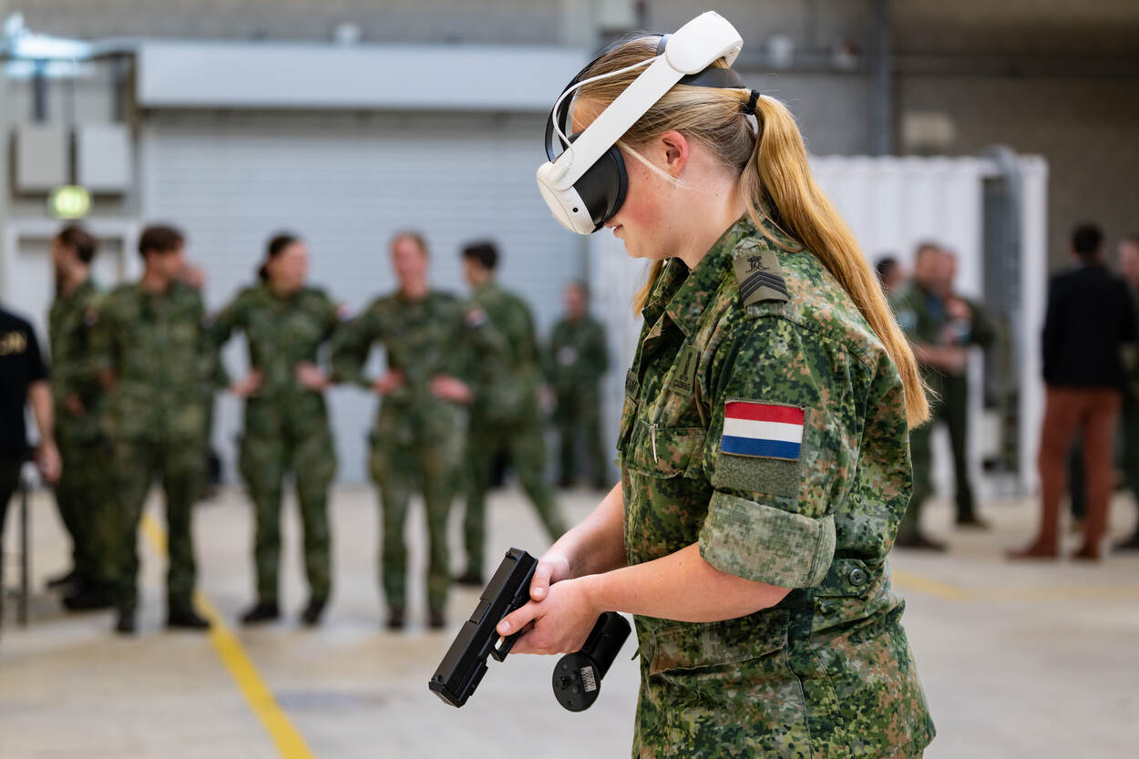Een militair loopt rond met een VR-bil op haar hoofd en een Glock in haar handen.