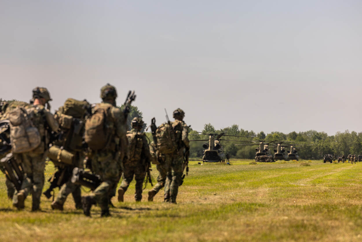 Militairen naderen openstaande Chinook transporthelikopters.
